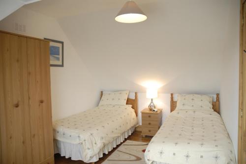 a bedroom with two beds and a lamp on a table at Seatown Cottage, Lossiemouth in Lossiemouth