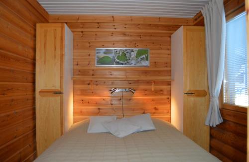 1 dormitorio con 1 cama con pared de madera en Rinnetupa Apartment en Tahkovuori