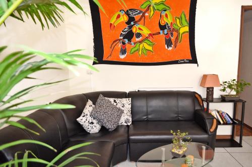 a leather couch in a living room with a painting at Guesthouse Casa Lapa in Alajuela City