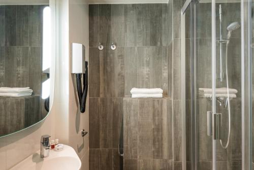uma casa de banho com um chuveiro, um lavatório e um espelho. em ibis Clichy Centre Mairie em Clichy