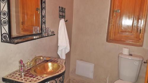 baño con lavabo de oro y aseo en Riad La Porte des 5 Jardins, en Marrakech