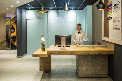 a man standing behind a reception desk in a office at ibis Clichy Centre Mairie in Clichy
