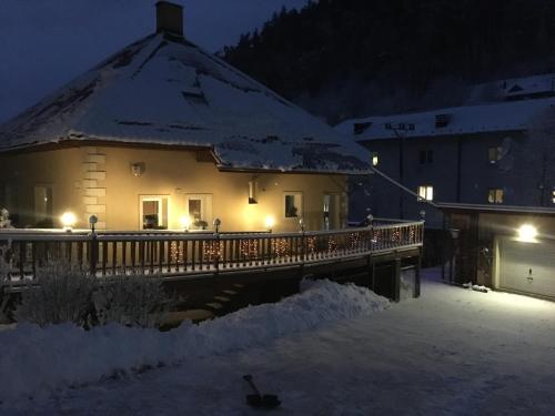 uma casa com uma ponte na neve à noite em Privát Adriana em Kremnica