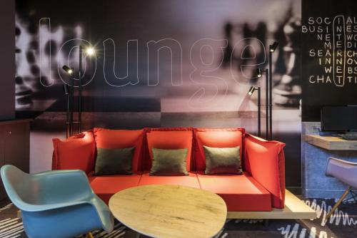 a living room with a red couch and a table at ibis Clichy Centre Mairie in Clichy