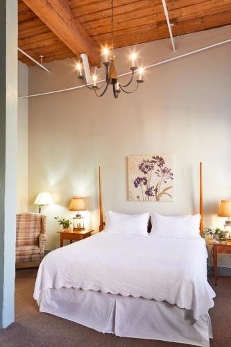 a bedroom with a large white bed with a chandelier at The Historic Brookstown Inn, Trademark Collection by Wyndham in Winston-Salem
