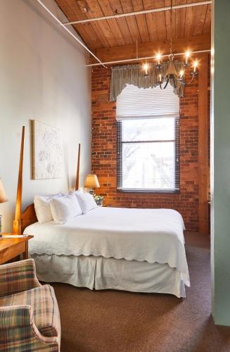 a bedroom with a large bed and a brick wall at The Historic Brookstown Inn, Trademark Collection by Wyndham in Winston-Salem