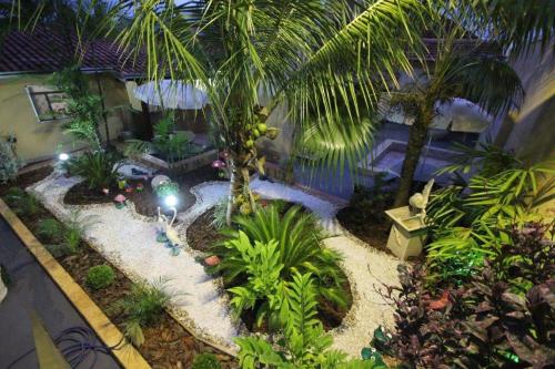 a garden with a palm tree and a swimming pool at Pousada Rozam in Olímpia