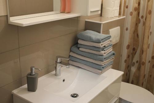 a bathroom with a sink and a pile of towels at Apartments Valentino in Gradac