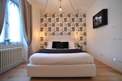 a bedroom with a white bed with a black blanket at Lainez Rooms & Suites in Trento