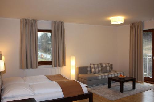 a bedroom with a bed and a couch and a window at Villa Malina in Oščadnica