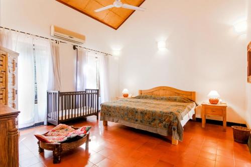 a bedroom with a bed and a chair at IKSHAA Luxury Villa with Private Pool in Majorda