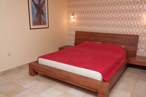 1 dormitorio con cama de madera y manta roja en Apartments LILA AUREA, en Petrovac na Moru