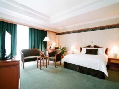 a large hotel room with a bed and a chair at Grand Palace Hotel in Miri