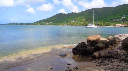 a boat in the water with rocks in the foreground at Sunset Lane in Laborie