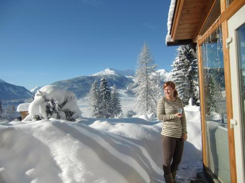 a woman standing outside of a house in the snow at Tannenhof in Ehrwald