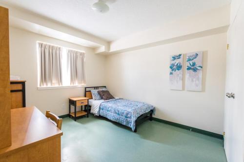 1 dormitorio con cama, mesa y ventana en United College, en Waterloo