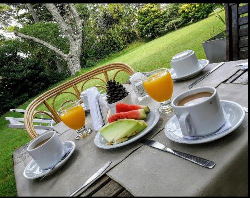 un tavolo con una tazza di caffè e un piatto di frutta di Silenios a Pinamar