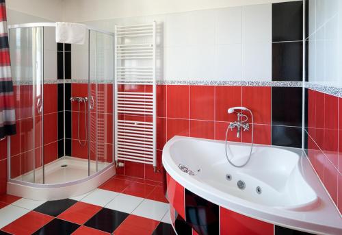 uma casa de banho vermelha e branca com uma banheira e um chuveiro em Penzion Zelený Dvor em Veľká Lomnica