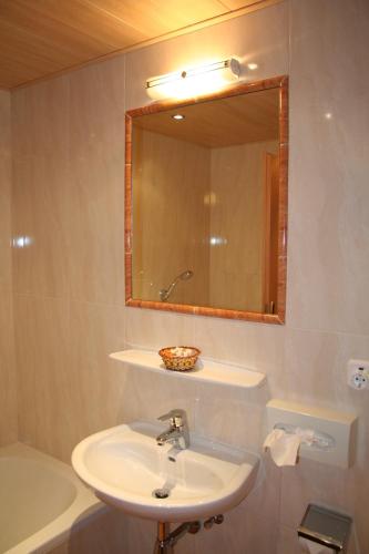 a bathroom with a sink and a mirror and a tub at Wellness Pension Hollaus in Kirchberg in Tirol