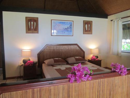 - une chambre avec un grand lit orné de fleurs violettes dans l'établissement Hotel Les Tipaniers, à Hauru