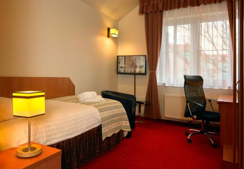 a hotel room with a bed and a desk and chair at Aura - Hotel & Restaurant & Sauna in Zielona Góra