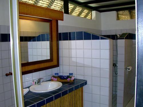 a bathroom with a sink and a mirror at Hotel Les Tipaniers in Hauru