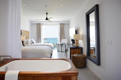 a large bathroom with two beds and a bath tub at Hotel El Ganzo - Adults Only in San José del Cabo