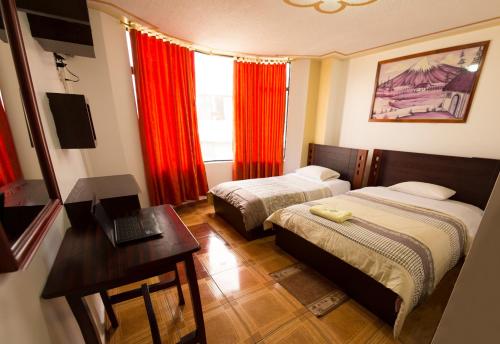 a bedroom with two beds and a desk with a laptop at Mashy´s Hostal in Otavalo
