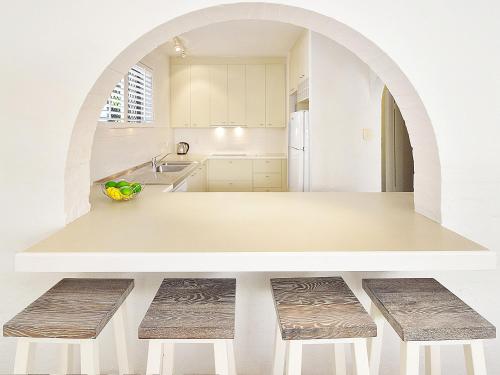 una cocina blanca con encimera y taburetes en Bayona Apartments, en Noosa Heads