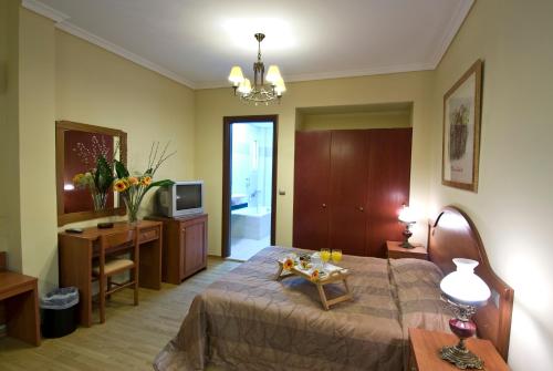 een slaapkamer met een bed en een televisie en een tafel bij Villa Elia in Veria