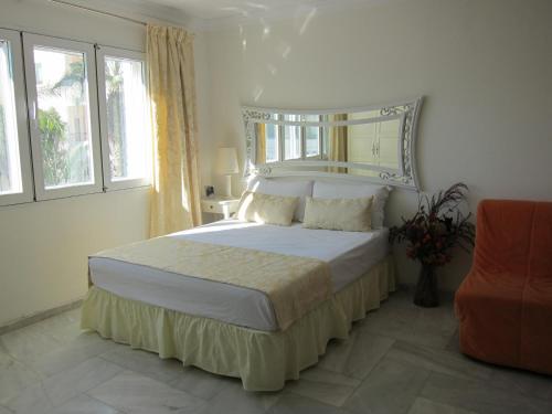 a bedroom with a bed and a chair and windows at Puerto marina in Benalmádena