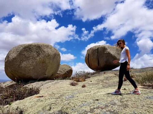 a woman walking on a rock near two large rocks at Pousada Vale Encantado in Serra de São Bento