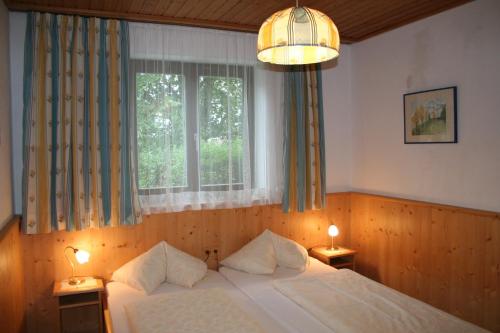 ein Schlafzimmer mit einem Bett, einem Fenster und zwei Lampen in der Unterkunft Wellness Pension Hollaus in Kirchberg in Tirol