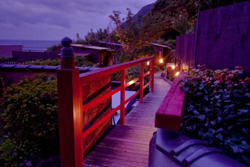 a wooden walkway with a bench on the side of a building at Hiina in Higashiizu