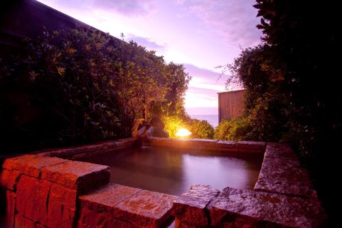a pool of water in a brick wall with the sunset at Hiina in Higashiizu