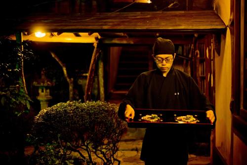 a man dressed in black holding a tray of food at Yamagaso in Hakone