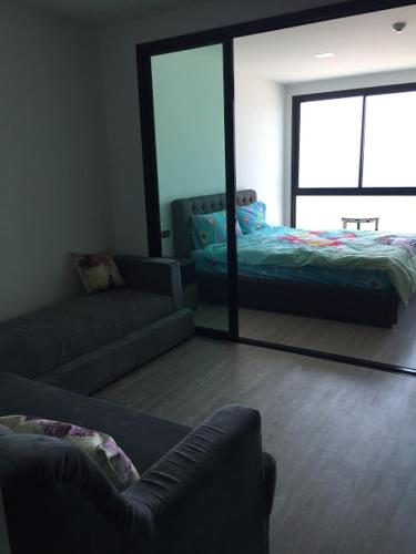 a living room with a couch and a mirror at The High One Condo B in Ban Laem Thaen