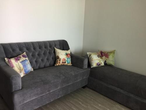 a gray couch with pillows on it in a room at The High One Condo B in Ban Laem Thaen