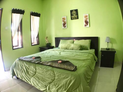 ein grünes Schlafzimmer mit einem Bett und einem Tablett darauf in der Unterkunft Tegal Homestay in Sanur