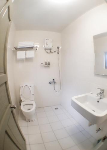a white bathroom with a toilet and a sink at Feb hostel in Tainan