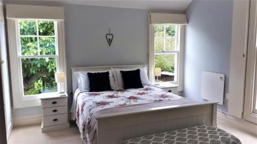 a white bedroom with a bed and two windows at The Saddlery in Greytown