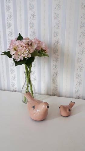 two birds and a vase with flowers in it at The Saddlery in Greytown