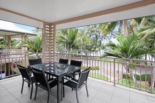 a balcony with a table and chairs and palm trees at Mantra Amphora in Palm Cove