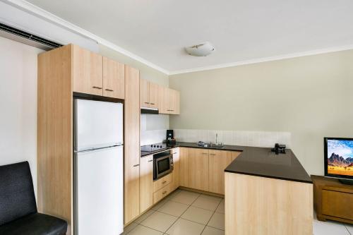 a kitchen with wooden cabinets and a white refrigerator at Mantra Amphora in Palm Cove