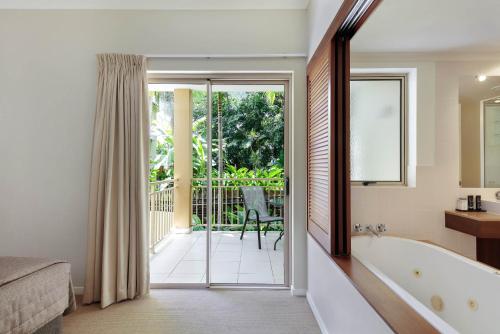 a bathroom with a tub and a bed and a balcony at Mantra Amphora in Palm Cove