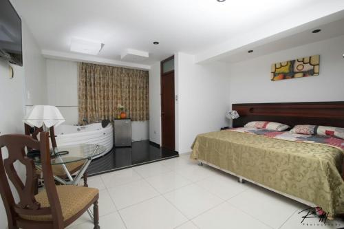 a bedroom with a bed and a tub and a table at Hotel Costa Andina in Moche