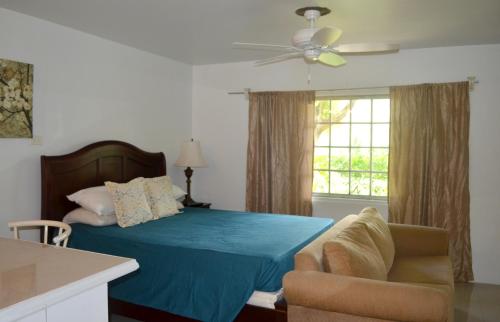 a bedroom with a blue bed and a chair and a window at One Love Cozy Studio Seawind On The Bay in Montego Bay