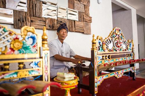 a man standing next to a bed in a room at Jimbaran Bay Beach Resort and Spa by Prabhu in Jimbaran