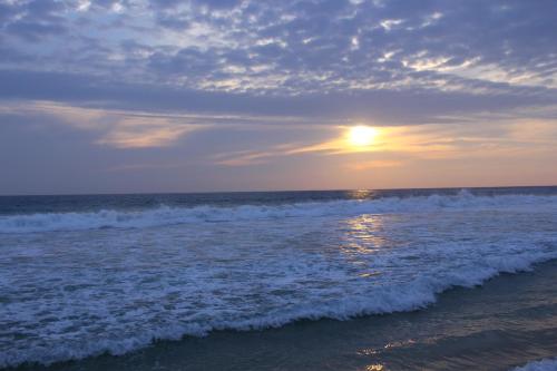 a sunset over the ocean with the waves at The Long Beach Resort & Spa in Koggala