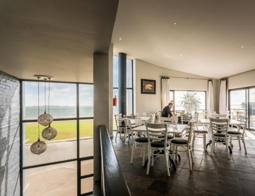 una sala da pranzo con tavoli, sedie e una finestra di Oyster Box Guesthouse a Walvis Bay